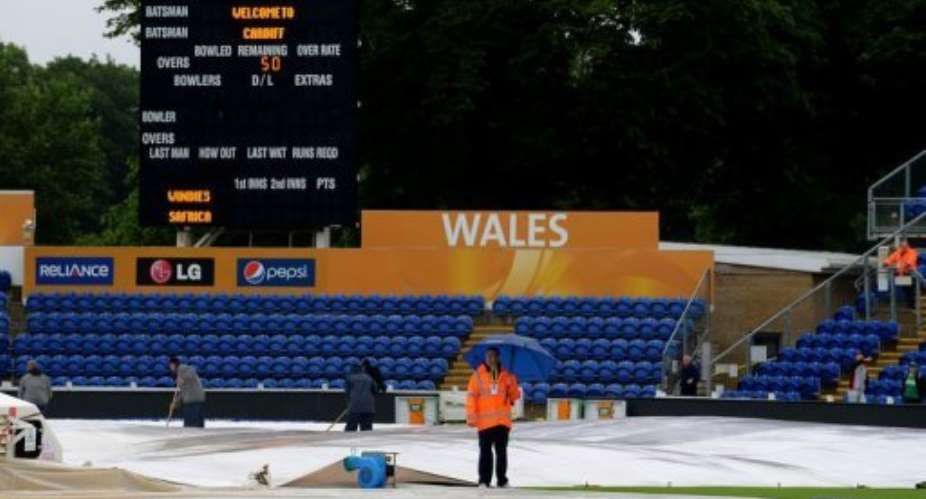 Members of the groundstaff remove water from the covers at the Cardiff Wales Stadium on June 14, 2013.  By Andrew Yates (AFP)