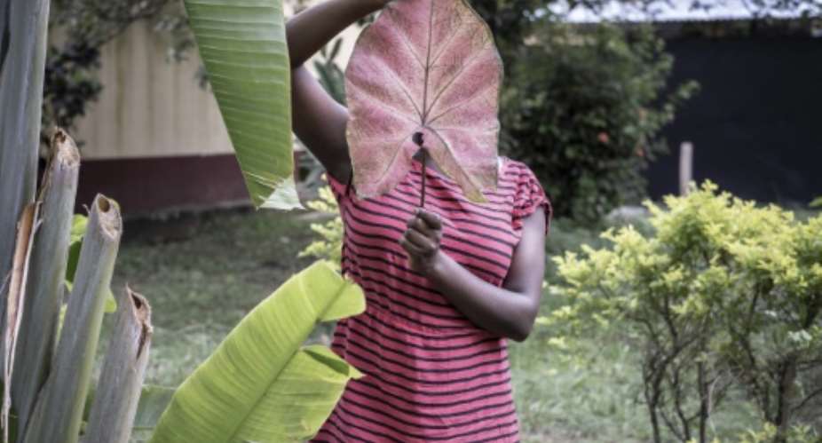 Rape epidemic: A 15-year-old victim of sexual assault in the Central African Republic hides her face behind a large leaf.  By Barbara DEBOUT AFP