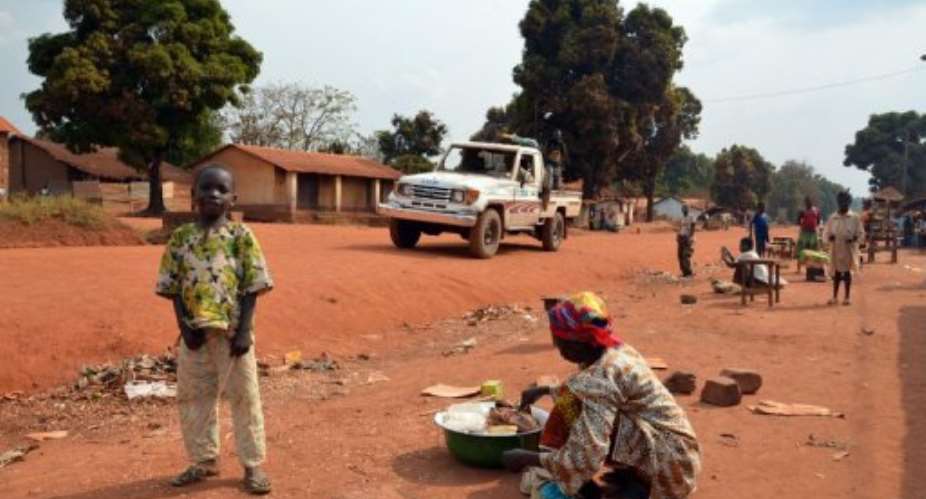 A woman sells goods on January 17, 2013, in Sibut north of Damara, as a rebel Seleka pickup truck patrols the village.  By Patrick Fort (AFP/File)