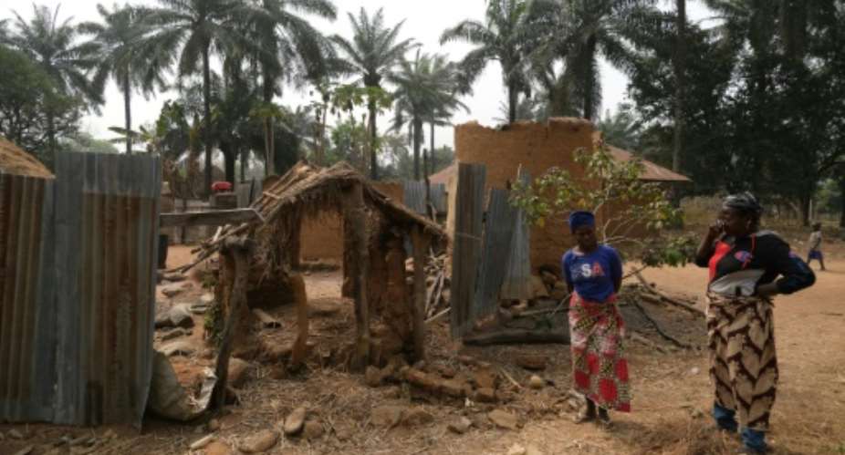 Relatives of the late chief of Manga village stand outside their burnt house.  By Kola Sulaimon AFP