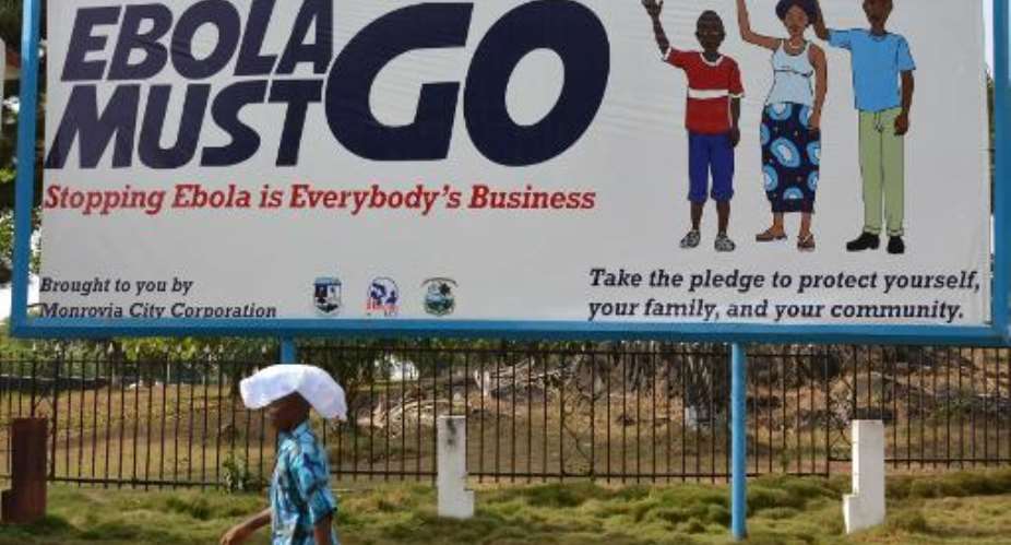 A man walking past an Ebola campaign banner with the new slogan Ebola Must GO in Monrovia, Liberia, on February 23, 2015.  By Zoom Dosso AFPFile