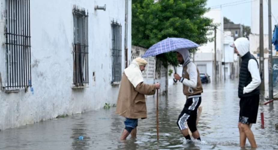 Residents wade across a flooded street in La Goulette, near the capital Tunis, after heavy rainfall swept Tunisia.  By FETHI BELAID (AFP)