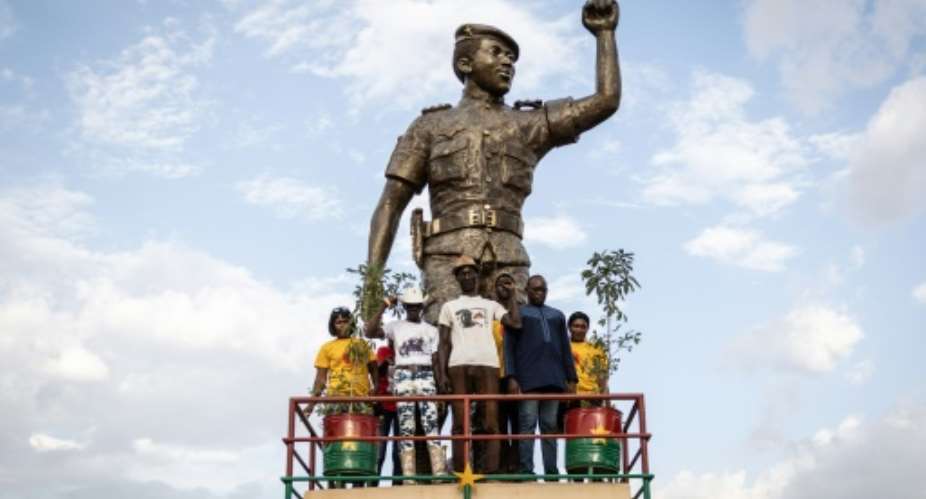 Revolutionary figure: People pose next to a statue of Sankara in Ouagadougou at ceremonies to mark the 34th anniversary of his assassination.  By OLYMPIA DE MAISMONT AFP