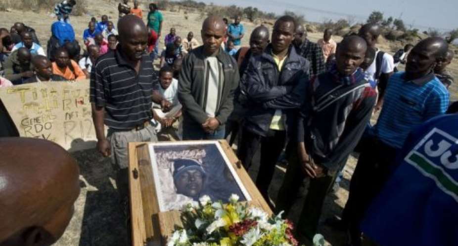 Mineworkers pray over the coffin containing the body of Mpuzeni Ngxande.  By Rodger Bosch AFPFile