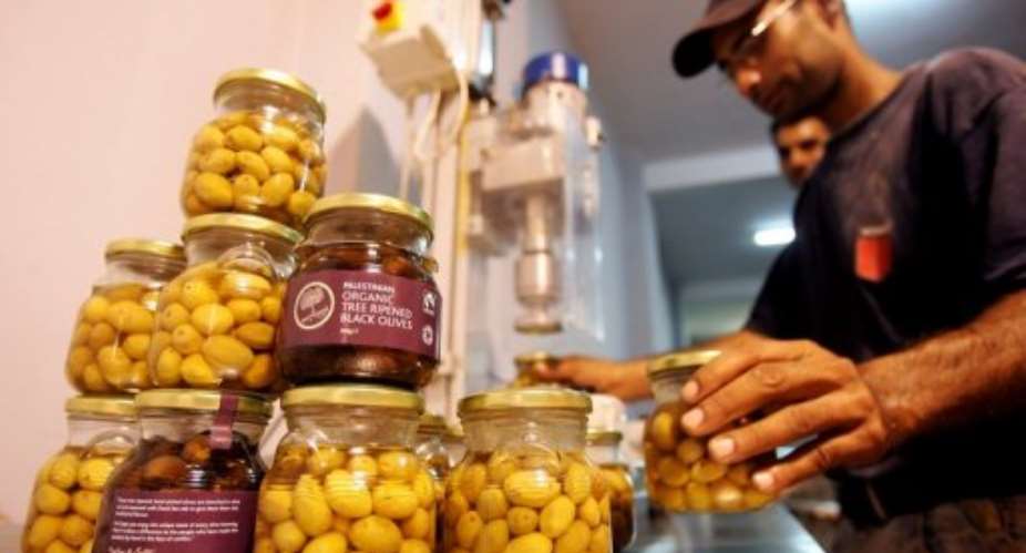 A Palestinian man organizes jars of olives grown in the West Bank.  By Saif Dahlah AFPFile