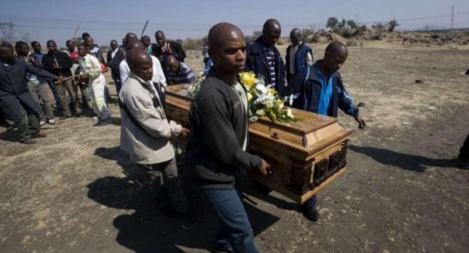 A group of men carry the body of a miner near the Lonmin mine in Marikana.  By Rodger Bosch AFP