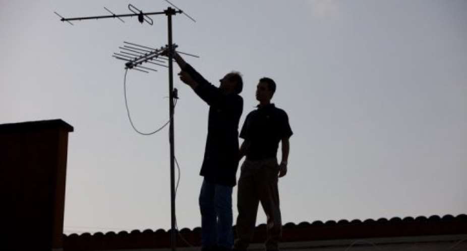 Two men try to position their television antenna for better reception on June 22, 2010 in Durban.  By Yasuyoshi Chiba AFPFile