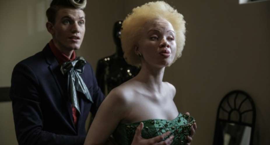 South African lawyer and fashion model Thando Hopa R tries on an evening dress by fashion designer Gert-Johan Coetzee at his workshop on June 13, 2015 in Johannesburg.  By Gianluigi Guercia AFP