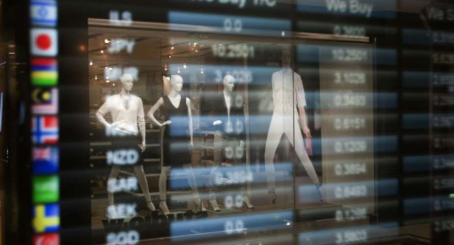 Mannequins from a clothing store are reflected on the window of a currency exchange, at the Victorian Alfred Waterfront, a popular shopping and entertainment complex, on January 11, 2014 in Cape Town, South Africa.  By Rodger Bosch AFPFile