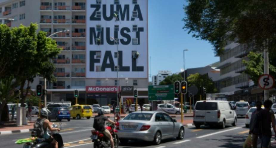 A giant banner, Zuma must fall, referring the South African president, Jacob Zuma, hangs down the side of a building on January 15, 2016, on Long street, Cape Town.  By Rodger Bosch AFPFile