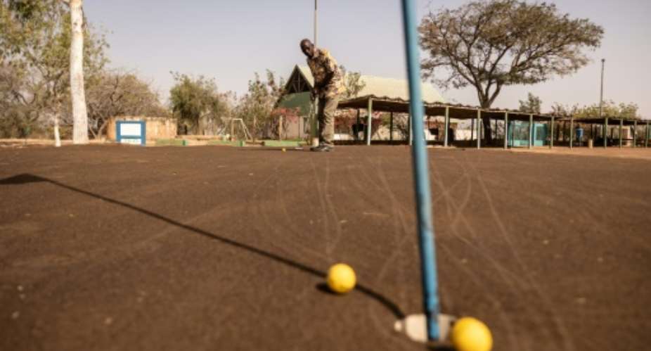 Salif Samake, president of Ouagadougou Golf Club, plays on the 'brown', a mixture of sand and waste oil.  By OLYMPIA DE MAISMONT AFP