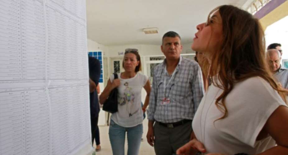 Salwa Smaoui, wife of jailed Tunisian presidential candidate Nabil Karoui, looks for her name before casting her ballot on Sunday.  By MOHAMED KHALIL AFP