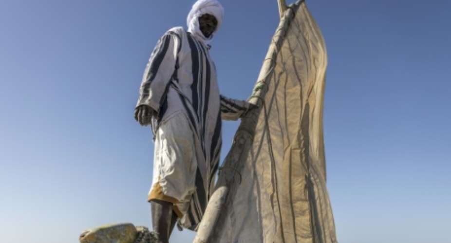 Samata Mahmoud unfurls the sail on his lanche boat in Mauritanias Banc dArguin National Park.  By PATRICK MEINHARDT (AFP)