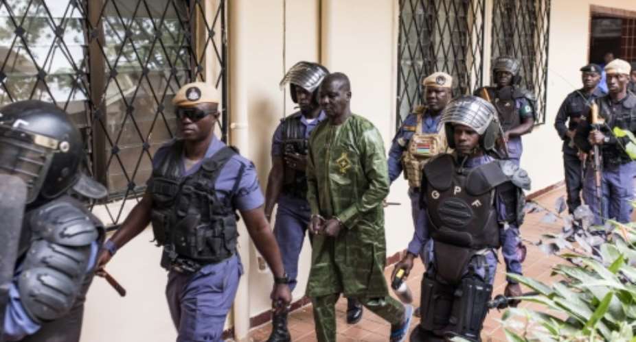 Security officers escort Sanna Manjang (C), a former member of The Gambias Junglers death squad, as he arrives at court.  By Muhamadou BITTAYE (AFP)