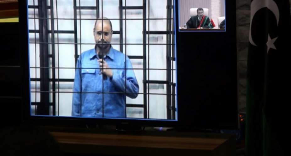 Seif al-Islam Kadhafi is seen in a video conference from Zintan answering a judge in Tripoli during his trial in 2014. A year later the court sentenced him to death for crimes committed during the 2011 uprising that ousted his father's regime.  By MAHMUD TURKIA AFP