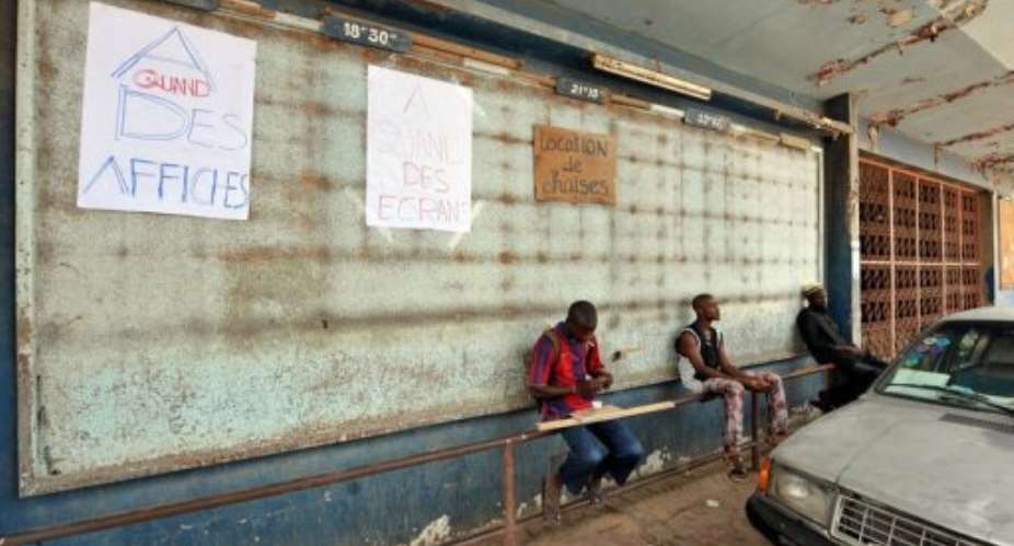 People sit in front of a long closed Cinema Liberte movie theater.  By Seyllou (AFP/File)