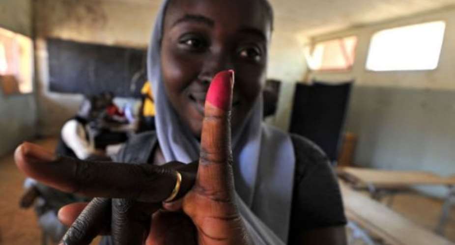 A woman displays her inked finger after voting at a polling station in Fatick.  By Issouf Sanogo AFPFile