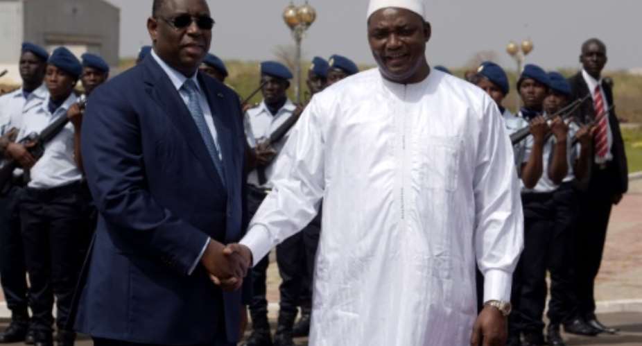 Senegalese president Macky Sall (L) shakes hands with his Gambian counterpart Adama Barrow upon his arrival at Dakar airport for a three-day official visit to Senegal, on March 2, 2017.  By SEYLLOU (AFP/File)