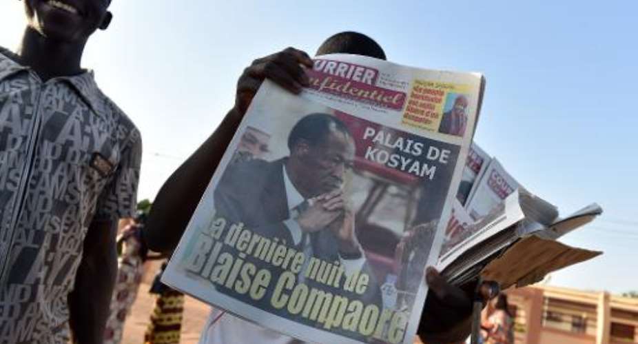 A man sells newspapers in a street of Ouagadougou on November 11, 2014, with headlines regarding the ouster of former president Blaise Compaore.  By Issouf Sanogo AFP