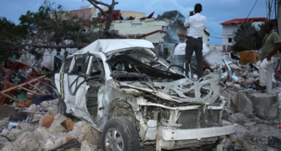 A man stands on rubble next to a destroyed car near the damaged Jazeera Palace hotel following a suicide attack in Mogadishu on July 26, 2015.  By  AFP