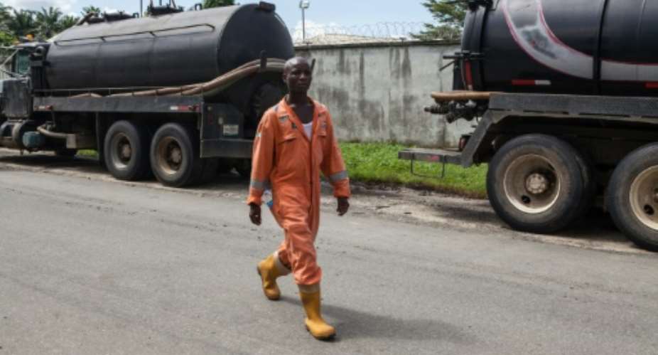 An employee walks past oil trucks at the Shell oil station in Port Harcourt, Nigeria on September 30, 2015.  By Florian Plaucheur AFPFile