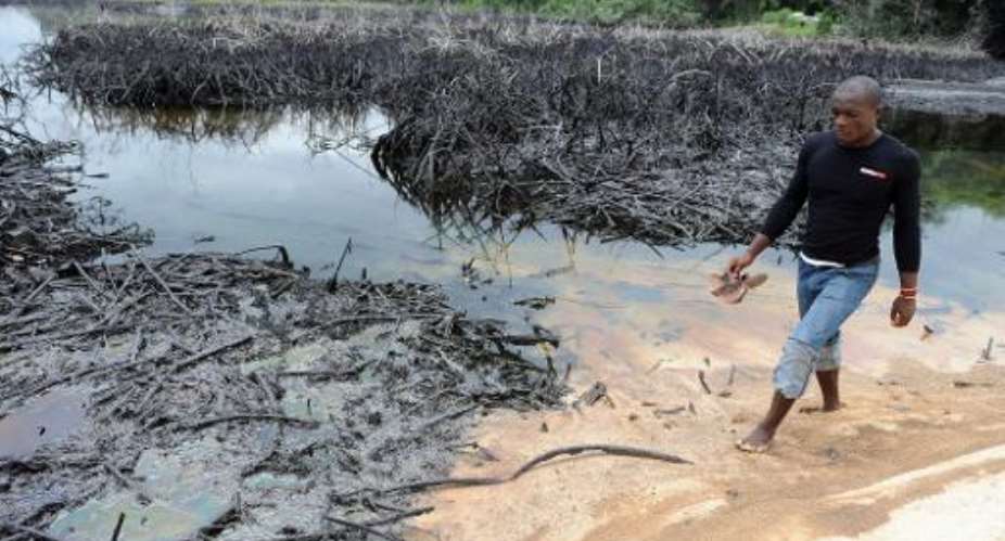 A man walks near spilled crude oil in the waters of the Niger Delta swamps of Bodo, a village in the famous Nigerian oil-producing Ogoniland, which hosts the Shell Petroleum Development Company, on June 24, 2010.  By Pius Utomi Ekpei AFPFile