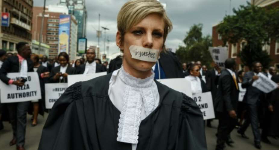 Silenced by injustice: one lawyer marched in silence with a piece of masking tape over her mouth.  By Jekesai NJIKIZANA (AFP)