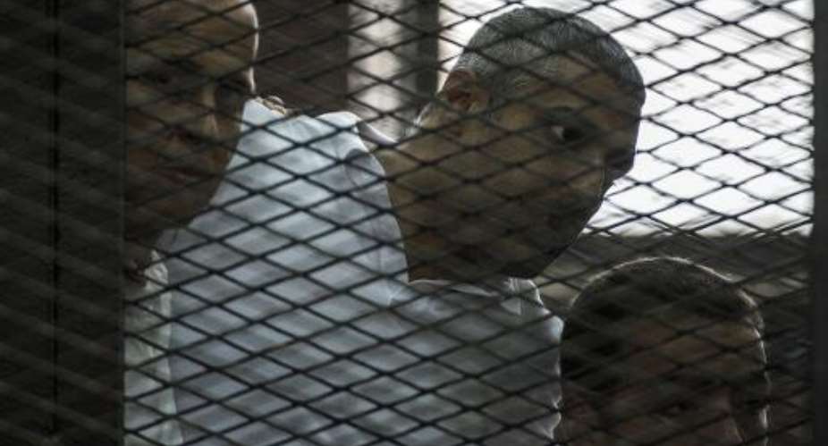 Al-Jazeera journalists Peter Greste L, Mohamed Fadel Fahmy C and Baher Mohamed R, seen in the defendants cage during their trial in Cairo in June.  By Khaled Desouki AFPFile
