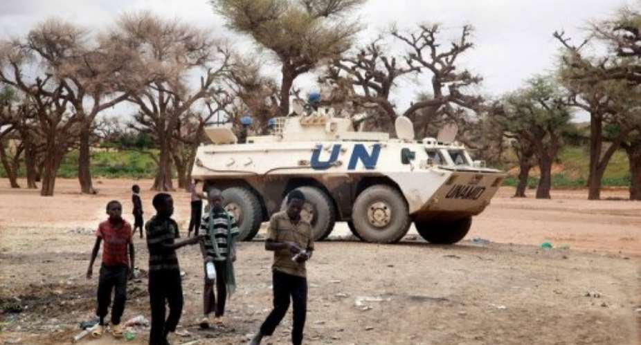 Sudanese boys walking past a UNAMID armoured personnel carrier patrolling Kutum in North Darfur.  By Albert Gonzalez Farran AFPUNAMIDFile