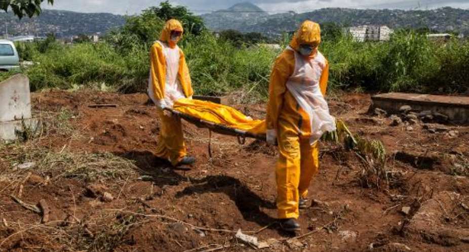 A team of Ebola funeral agents carry a body at the Fing Tom cemetery in Freetown, on October 10, 2014.  By Florian Plaucheur AFPFile