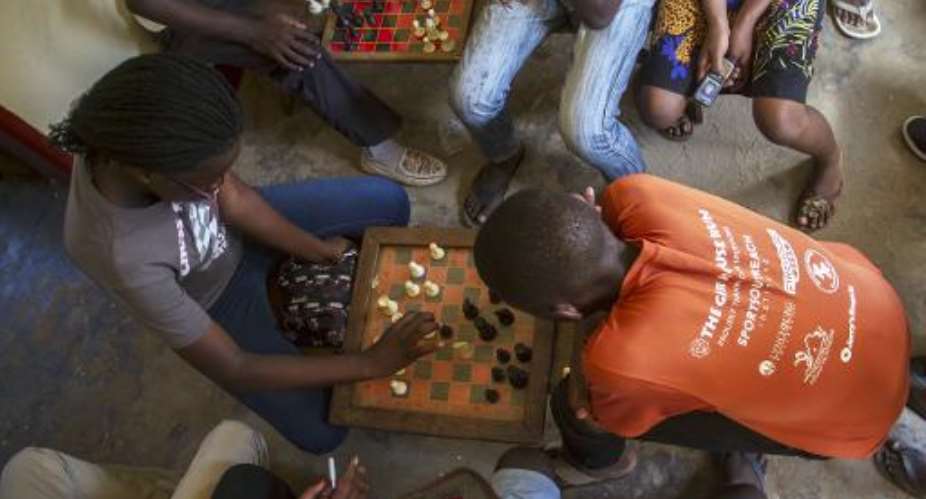 Phiona Mutesi L plays a game of chess with her colleagues at the chess academy in Kibuye, Kampala, on January 26, 2015.  By Isaac Kasamani AFP