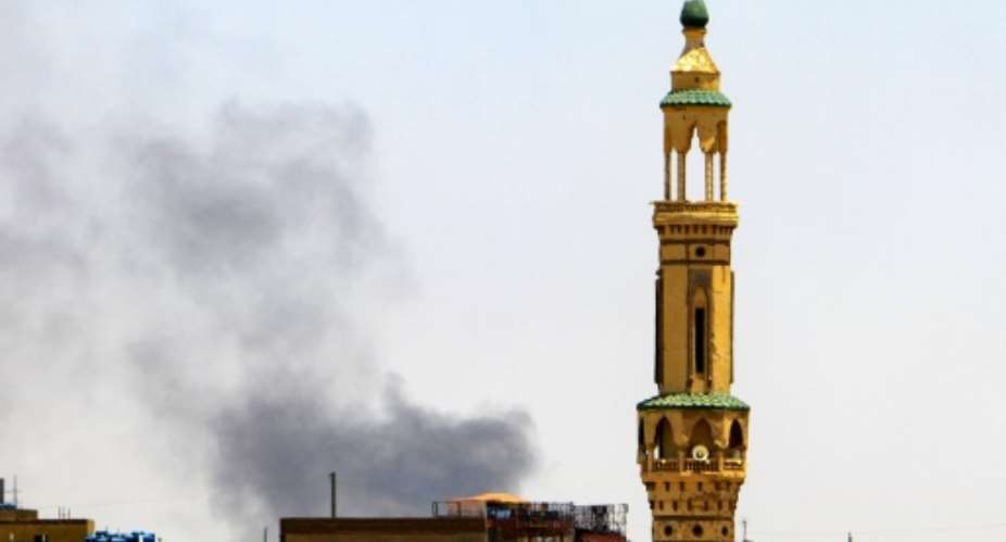 Smoke billows above buildings behind a mosque during fighting in Khartoum.  By - AFP