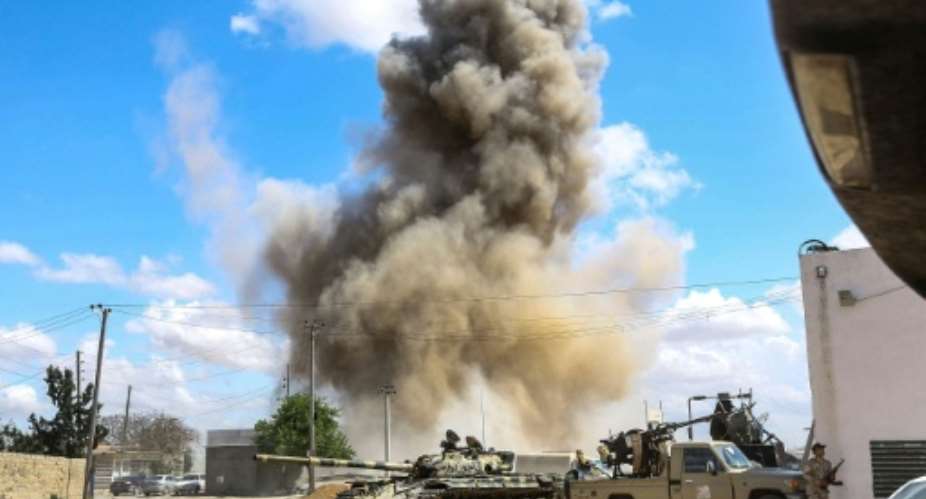 Smoke rises from an air strike behind a tank and pickup trucks of Libya's Government of National Accord during clashes in Wadi Rabie suburb south of the capital Tripoli..  By Mahmud TURKIA AFP