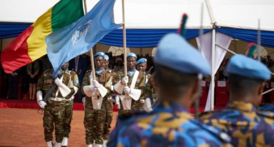 Soldiers hold the UN and Malian flags during a Peacekeepers' Day ceremony at the operating base of MINUSMA, the UN's mission in Mali, on May 28, 2018.  By Michele CATTANI AFPFile