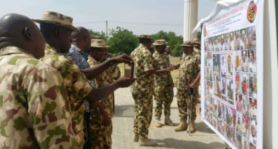 Soldiers take pictures of a banner with the Nigerian army's list of most wanted Boko Haram Islamists, in Maiduguri, on November 21, 2016.  By - AFPFile