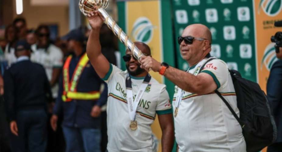South Africa captain Temba Bavuma (L) and coach Shukri Conrad hold the Mace in Johannesburg on Wednesay after winning the World Test Championship in London last weekend..  By PHILL MAGAKOE (AFP)