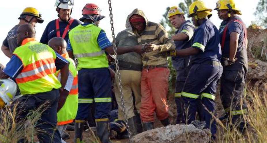 Rescuers tend to a mine worker (C) after he was pulled out from an illegal gold mine in Benoni, outside Johannesburg, on February 16, 2014.  By Alexander Joe (AFP)