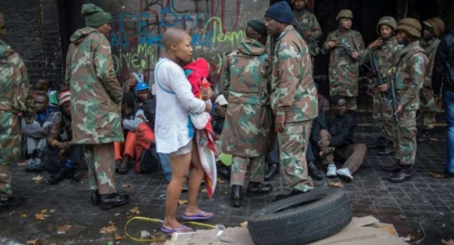 South African police officers and soldiers are seen with migrants after a 2015 raid in Johannesburg.  By MUJAHID SAFODIEN AFPFile
