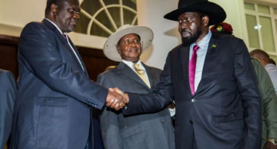 South Sudanese President Salva Kiir R shakes hands with opposition leader Riek Machar L during peace talks at Uganda's statehouse in Entebbe on July 7, 2018, ahead of their agreement to sign a preliminary power-sharing deal.  By SUMY SADURNI AFP