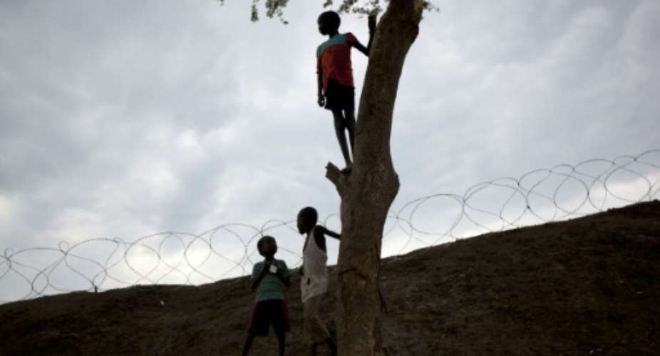 Boys play in and around a tree next to the perimeter fortifications of the United Nations Mission in South Sudan UNMISS base in Bentiu, South Sudan.  By Tristan McConnell AFP