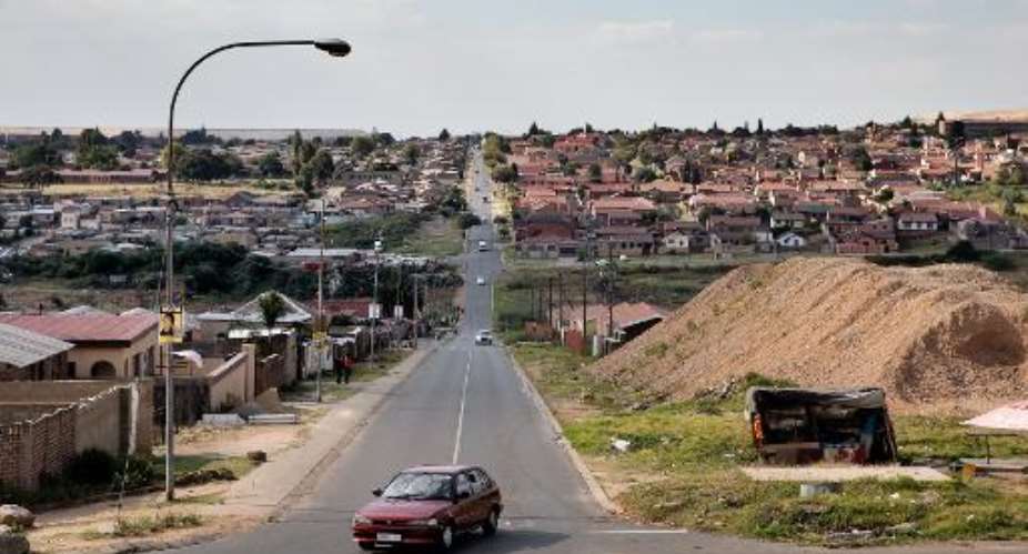 A car approaches an intersection in Soweto on April 15, 2014, visible in the background is a recently built urban development.  By Marco Longari AFPFile