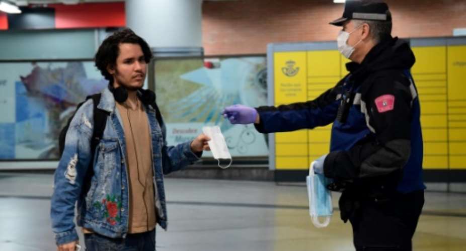 Spanish police officers handed out face masks to commuters as lockdown restrictions eased Monday.  By JAVIER SORIANO AFP