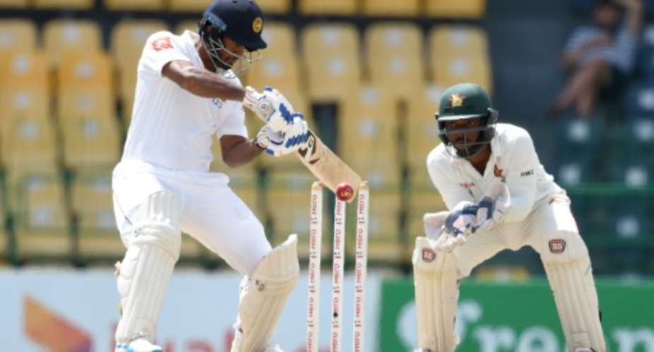 Sri Lanka batsman Dimuth Karunaratne plays a shot as Zimbabwe wicketkeeper Regis Chakabva looks on during the fourth day of the one-off Test match at the R Premadasa Cricket Stadium in Colombo on July 17, 2017.  By ISHARA S. KODIKARA AFP