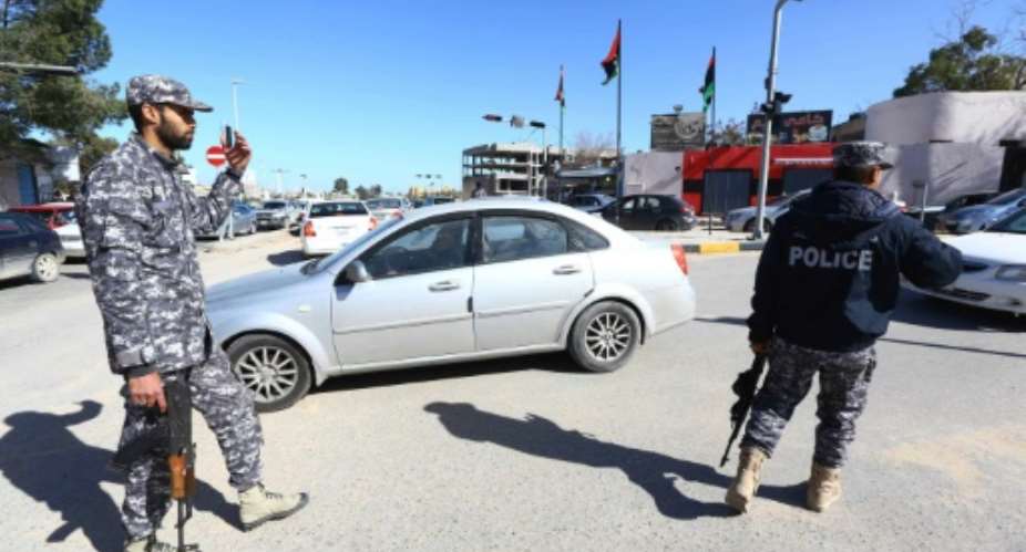 Libyan police guard a checkpoint in Tripoli.  By Mahmud Turkia AFP