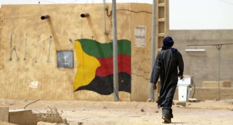 This picture taken on July 27, 2013 shows a man walking past a flag of the National Movement for the Liberation of Azawad MNLA painted on a wall in Kidal.  By Kenzo Tribouillard AFPFile