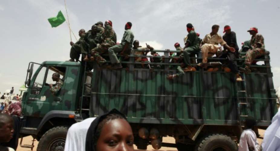 A Sudanese girl walks past a truck carrying soldiers in the West Darfur state capital of El Geneina on July 24, 2008.  By Khaled Desouki AFPFile