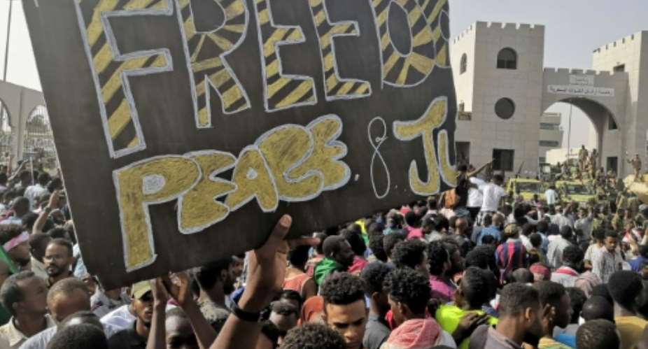 Sudanese anti-regime demonstrators holding up a banner calling for