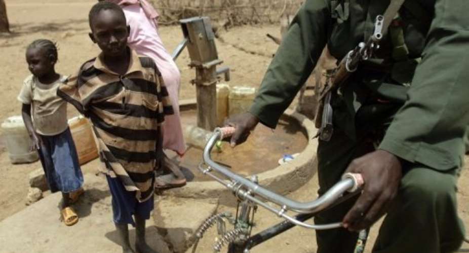 A Sudanese soldier rides a bicycle past a family in the town of Talodi in South Kordofan, April 12, 2012.  By Ashraf Shazly AFPFile