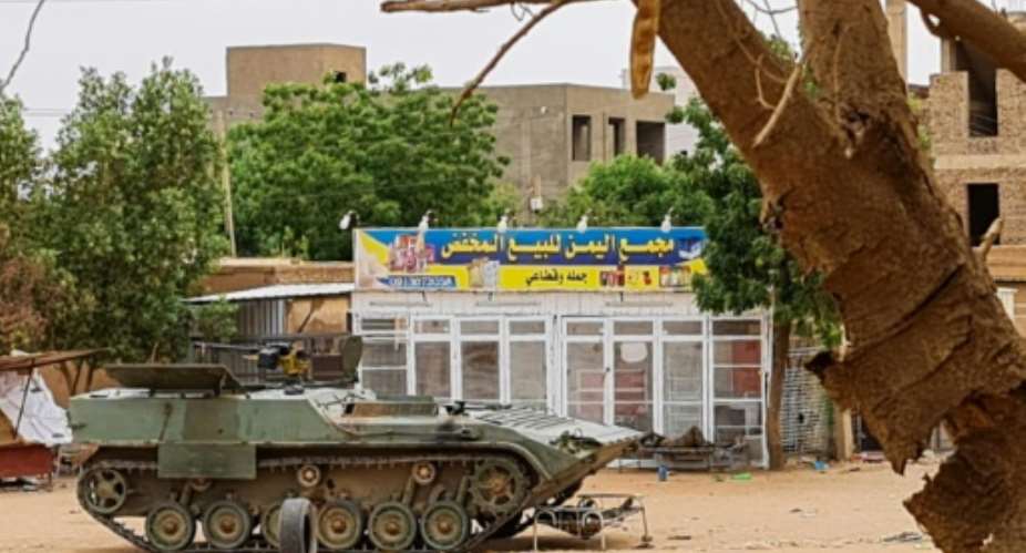 Sudanese Army soldiers rest beside an armoured vehicle at a checkpoint in Khartoum.  By - (AFP)