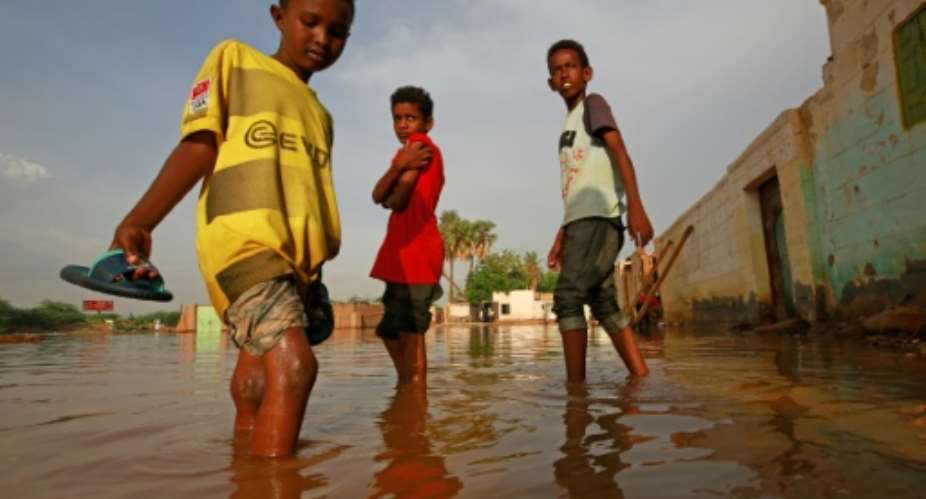 Sudanese boys make their way through a flooded street in the capital's twin city of Omdurman.  By ASHRAF SHAZLY AFP